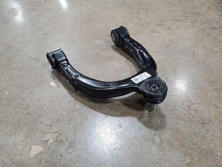 Tesla front suspension control arm area viewed from the engine bay with arrows